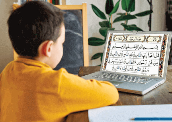 Young boy in skull cap learning on a laptop