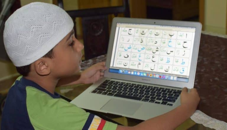 Young girl with hijab and headset learning on a laptop
